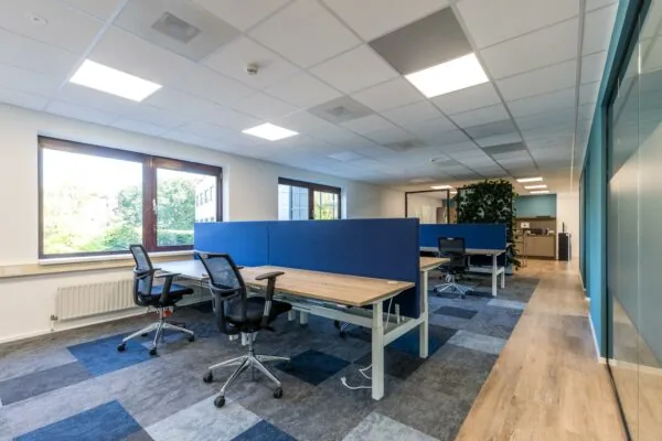 Moderne en lichte kantooruimte aan de Baarnsche Dijk met werkplekken, ergonomische stoelen en een groenaccentwand.